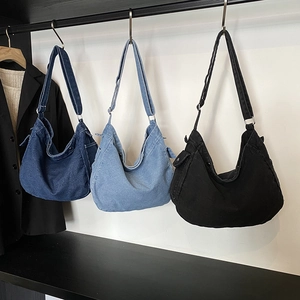 Trois sacs bandoulière en denim minimalistes bleu et noir suspendus sur un cintre