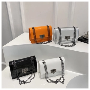 Close-up of four glossy patent leather crossbody bags with metal chains and locks