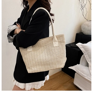 Detail of beige woven tote bag with white PU leather strap for summer commuting style