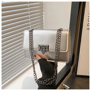 Detailed shot of silver metallic crossbody bag with black chain and turn-lock closure