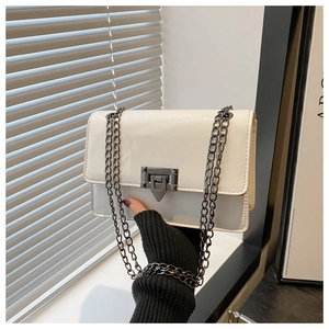 Close-up of a glossy white patent leather crossbody bag with a vintage dark grey metal lock