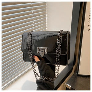 Detail of glossy black patent leather bag with a unique metallic clasp and chain strap