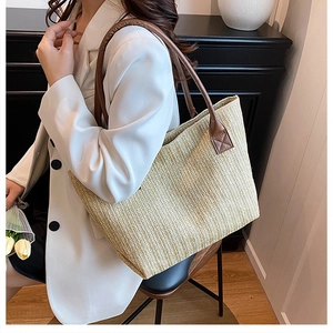 Detail of hand-woven tote bag with herringbone texture and brown leather handle