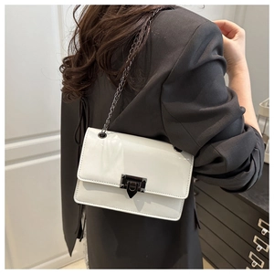 Close-up of a white patent leather shoulder bag with a metal buckle and chain strap