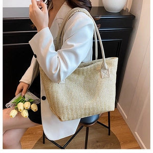 Dettaglio della borsa tote minimalista in paglia intrecciata con lunghi manici