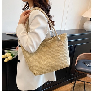 Dettaglio della borsa tote intrecciata beige con motivo a spina di pesce su modella
