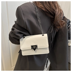 Detail showing white flap bag with dark metal chain strap on grey blazer