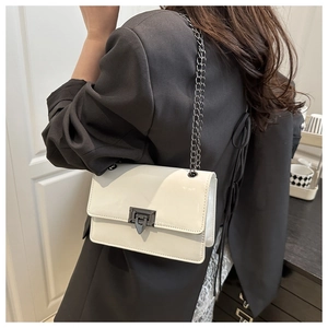 Detailed shot of white patent leather bag featuring glossy finish and black chain strap
