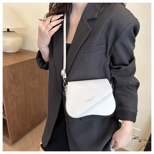 Close-up of white crossbody bag with asymmetric flap design and fashion logo lettering