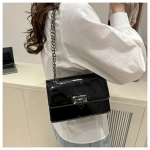 Detail of glossy black patent leather square bag with metallic chain and lock closure