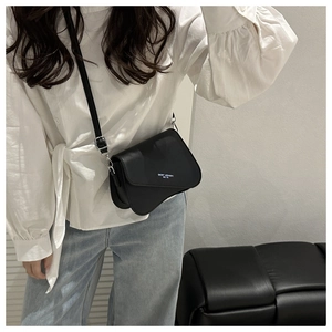 Detail of black faux leather crossbody bag with curved flap and white fashion typography