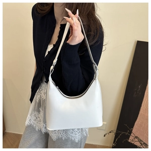 Minimalist white leather hobo bag with silver zipper shown on a model's shoulder