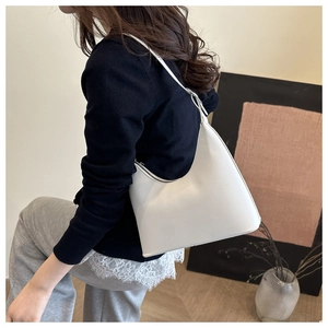 Minimalist white underarm bag side view showing sleek moon shape and smooth texture