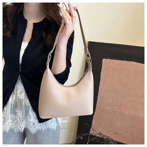 Side view of beige minimalist underarm bag with adjustable shoulder strap on model