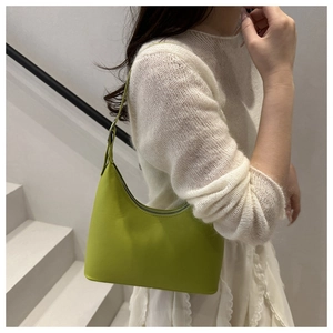 Lime green underarm bag shown as detail on model with a white knit top in minimal setting
