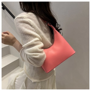 Pink crescent shoulder bag in vegan leather worn by a model in a minimalist setting