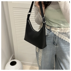 Detail of black hobo bag showing silver metal buckle and adjustable shoulder strap