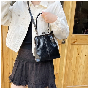 Detailed view of a vintage black shell bag featuring a metal clasp and leather texture