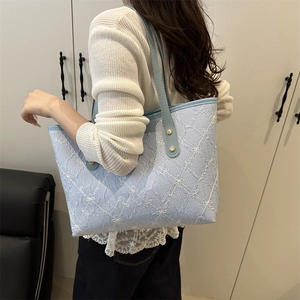 Borsa tote celeste trapuntata con ricami indossata da una modella per look casual