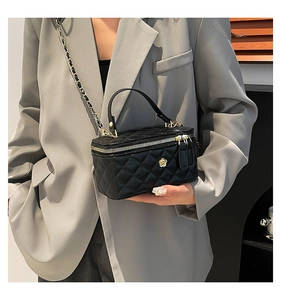Detail view of black quilted mini handbag with gold flower decor and chain strap