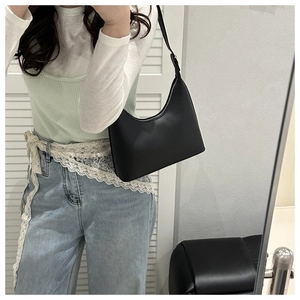 Mirror selfie showing a black minimalist underarm bag with silver zipper and sleek finish