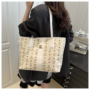 Detail of a beige leather tote with bear pattern shown from a back perspective on a model