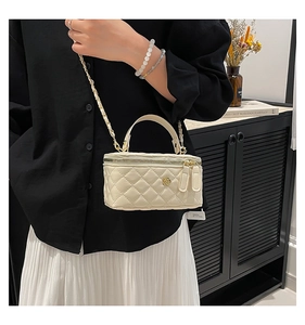 Detail of cream quilted mini bucket bag with gold camellia clasp and chain strap