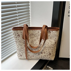 Close-up of woven tote bag featuring beige fabric with brown leather handles and trim