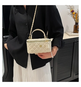 Close-up of white quilted mini bag with gold camellia logo and woven chain strap