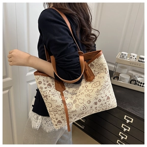 Detail of beige woven tote bag with brown leather trim and cartoon love graphic