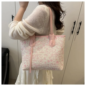 Detail of pink and white woven tote bag with leather handles shown in a side-carry view