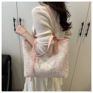 Detail of pink woven tote bag with leather straps and refined textured pattern