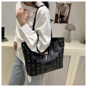 Detail of black tote bag with white cartoon bear pattern and lychee grain leather texture