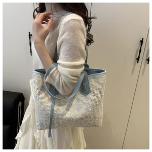 Detailed shot of the blue and beige woven floral pattern and leather shoulder strap