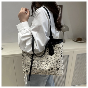 Detail of woven tote bag with artistic graffiti prints and black leather straps