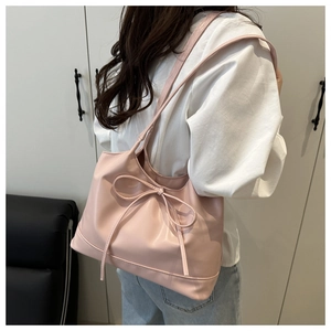 Detailed back view of a pink tote bag with a bow detail on a model's shoulder