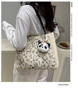 Detail of embroidered tote bag featuring black graffiti patterns and panda plush charm