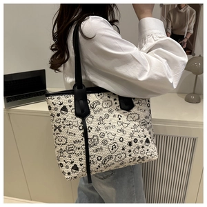 Detail of off-white woven tote bag with artistic black graffiti prints and slim shoulder strap