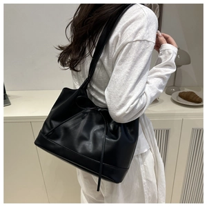 Detail of black leather tote bag with soft bow drawstring and spacious casual design