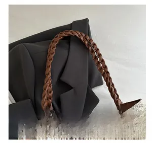 Détail de la poignée tressée marron et du motif floral beige sur le sac cabas