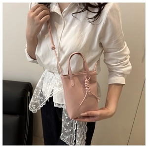 Vue détaillée du mini sac carré rose avec nœuds décoratifs et fine bandoulière