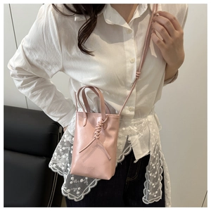 Détail d'un sac bandoulière rose clair avec nœud tressé élégant et logo embossé