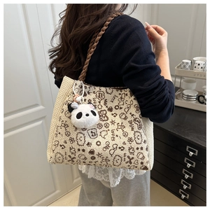 Détail du sac cabas tissé avec des graffitis marrons et un charmant panda en peluche