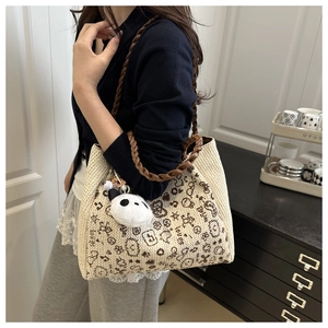 Close-up of woven cream backpack with brown handles, panda prints, and plush panda charm