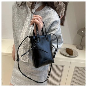 Dettaglio della borsa nera lucida con scritta Fashion Bags e tracolla con nodo