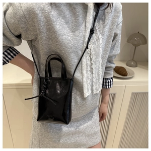 Dettaglio borsa per cellulare in pelle nera lucida con scritta Fashion Bags incisa