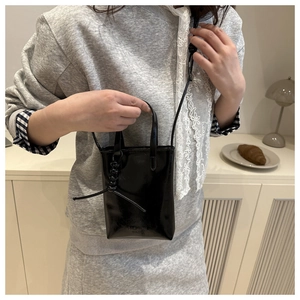 Dettaglio mini borsa in pelle lucida nera con scritta Fashion Bags goffrata sul fondo