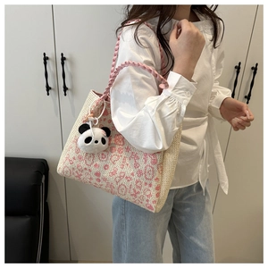 Detail of pink and beige woven tote bag with a cute panda pendant shown on model