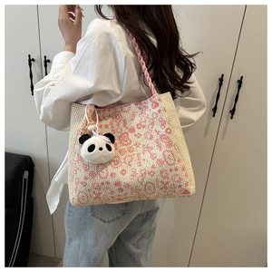 Detailed view of women's woven tote bag with pink floral print and cute panda pendant