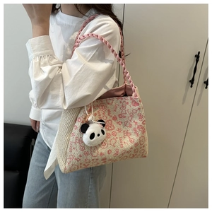 Detail der handgewebten Strohtasche mit rosa Leopardenmuster und süßem Pandabär-Anhänger